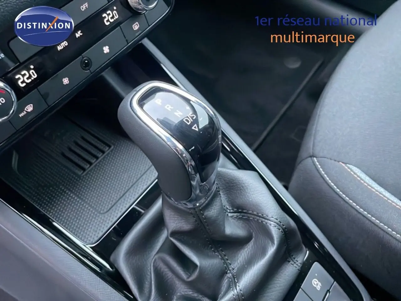 Gros plan sur le levier de vitesse automatique du Skoda Kamiq gris graphite, avec console centrale et siège tissu gris partiellement visibles.