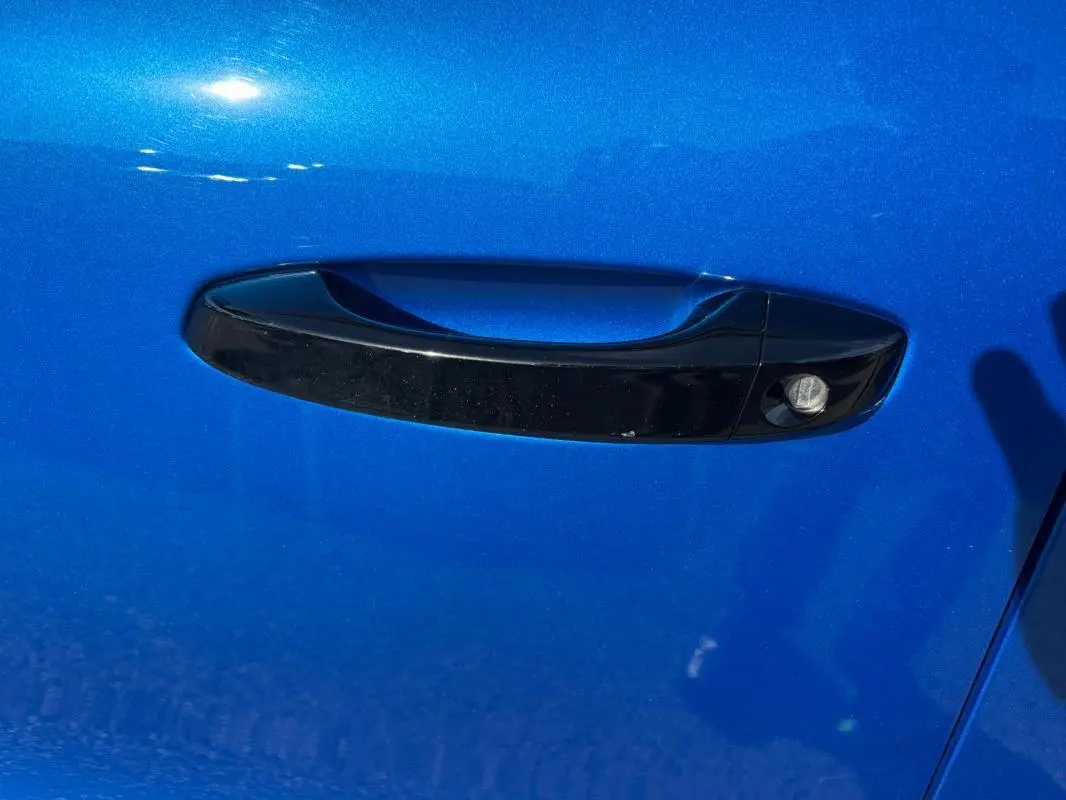 Poignée de porte noire sur la porte avant gauche d'une Citroën C3 bleu vif 2025, vue rapprochée.