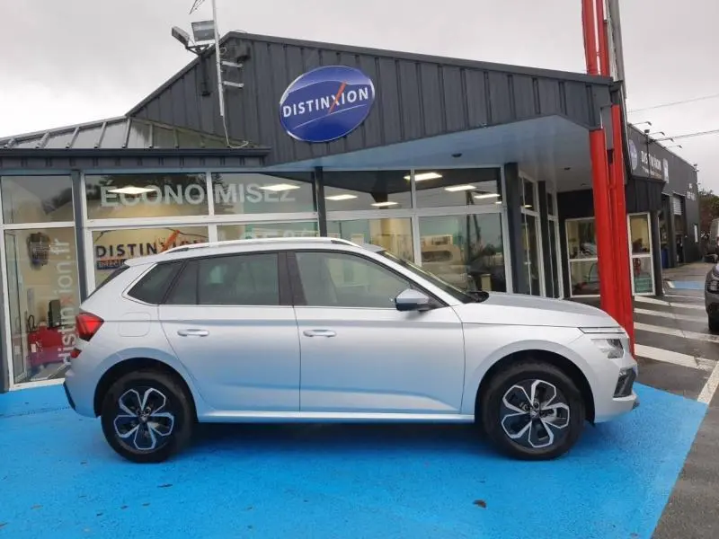 Vue de profil côté gauche d'un Skoda Kamiq gris diamant métallisé garé devant un showroom Distinxion.
