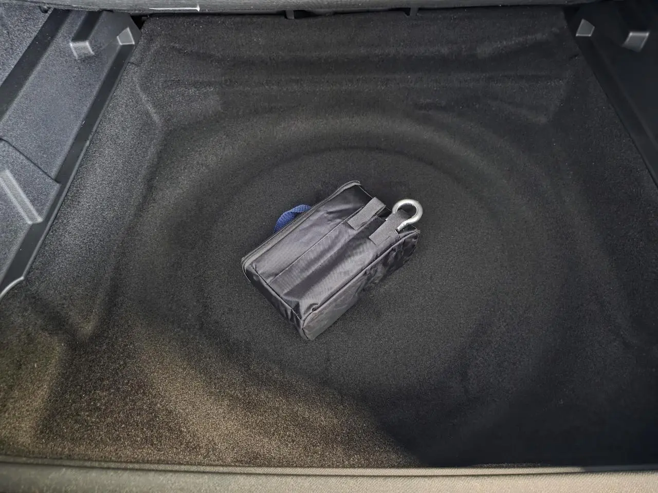 Coffre ouvert du Peugeot 3008 bleu, montrant le rangement sous plancher avec kit de dépannage pneumatique.