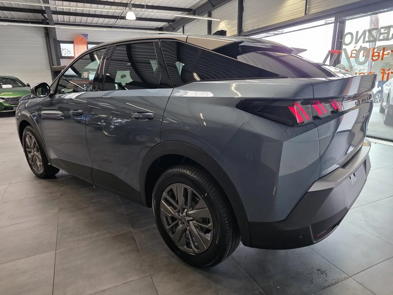 Vue 3/4 arrière droit d’un Peugeot 3008 hybride bleu avec feux arrière à LED en forme de griffes et jantes alliage 18 pouces.