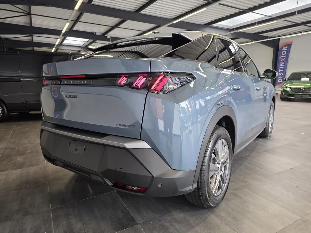Vue 3/4 arrière droit du Peugeot 3008 hybride bleu avec feux arrière à LED en forme de griffes et bandeau noir laqué.