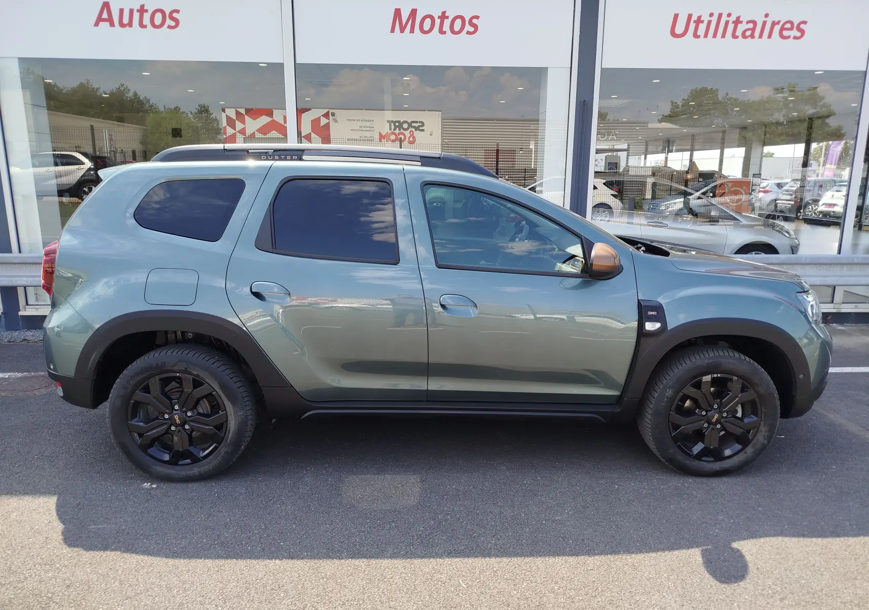 Profil droit du Dacia Duster 2024 Vert Cèdre métallisé avec jantes noires et rétroviseurs bronze, version 1.5 Blue dCi 115ch Extreme 4x4.