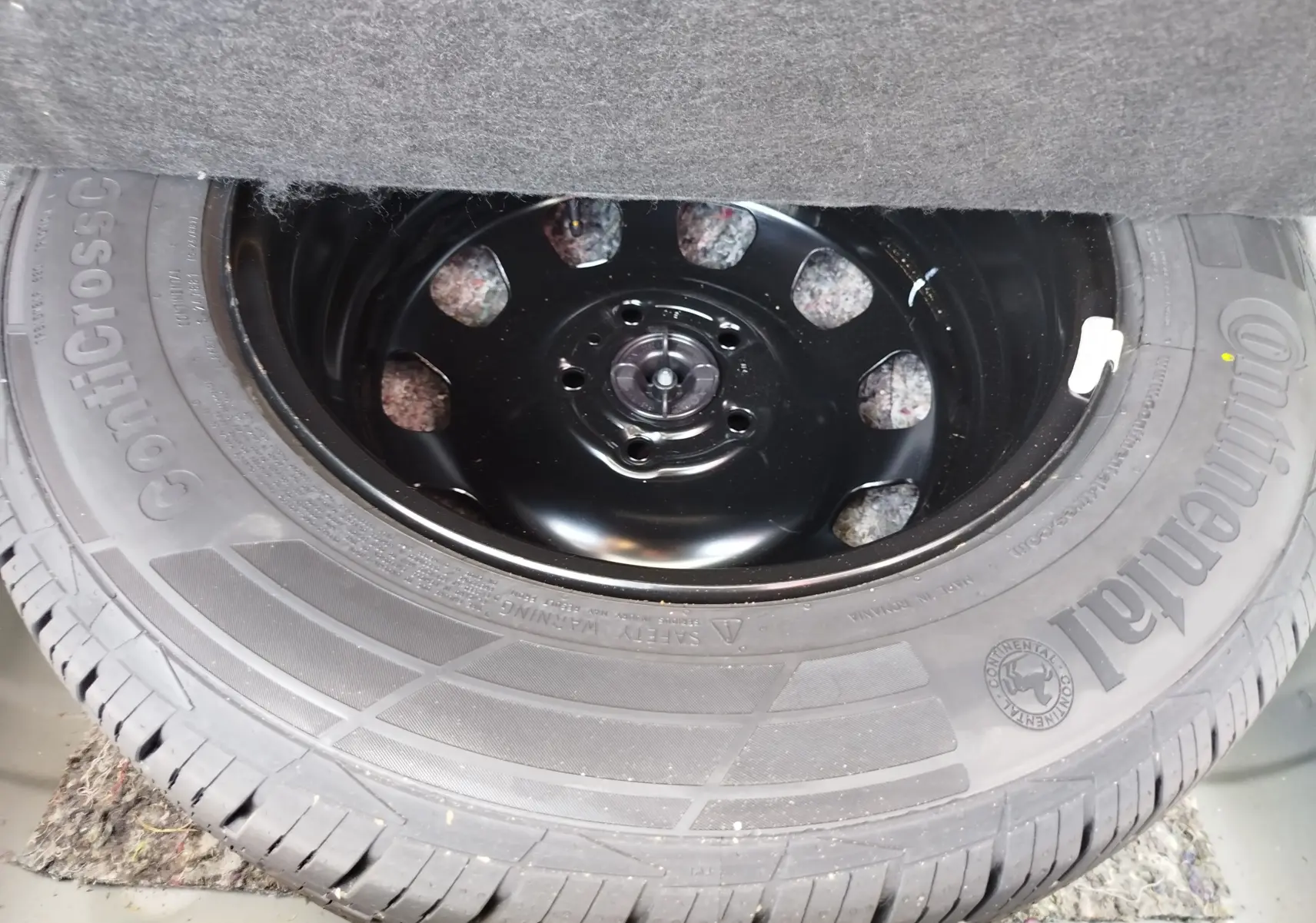 Roue de secours avec jante acier noire et pneu Continental ContiCrossContact visible dans le coffre d'un Dacia Duster 2024.