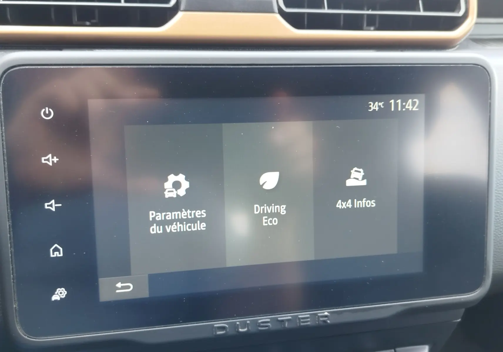 Écran tactile central du Dacia Duster 2024 affichant les options Paramètres, Driving Eco et 4x4 Infos, avec tableau de bord noir.