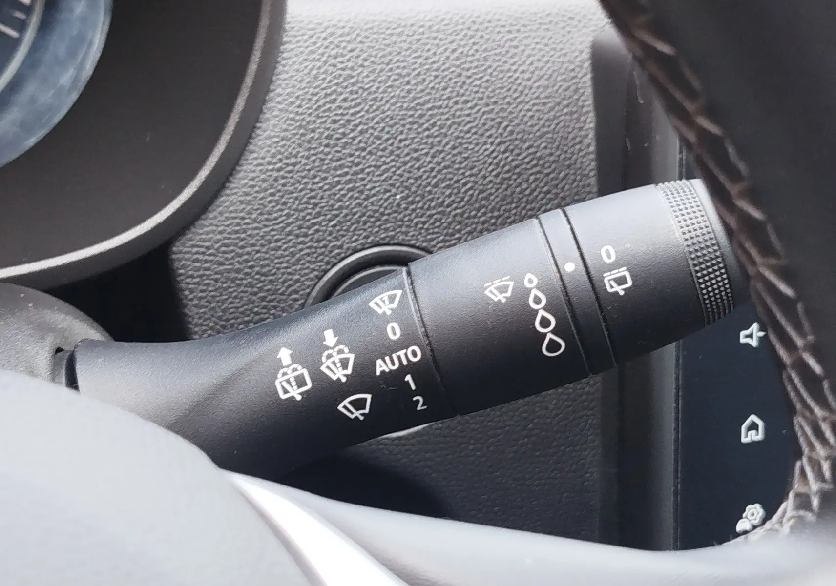 Gros plan sur la commande des essuie-glaces du Dacia Duster 2024, intérieur noir avec détails blancs sur levier.