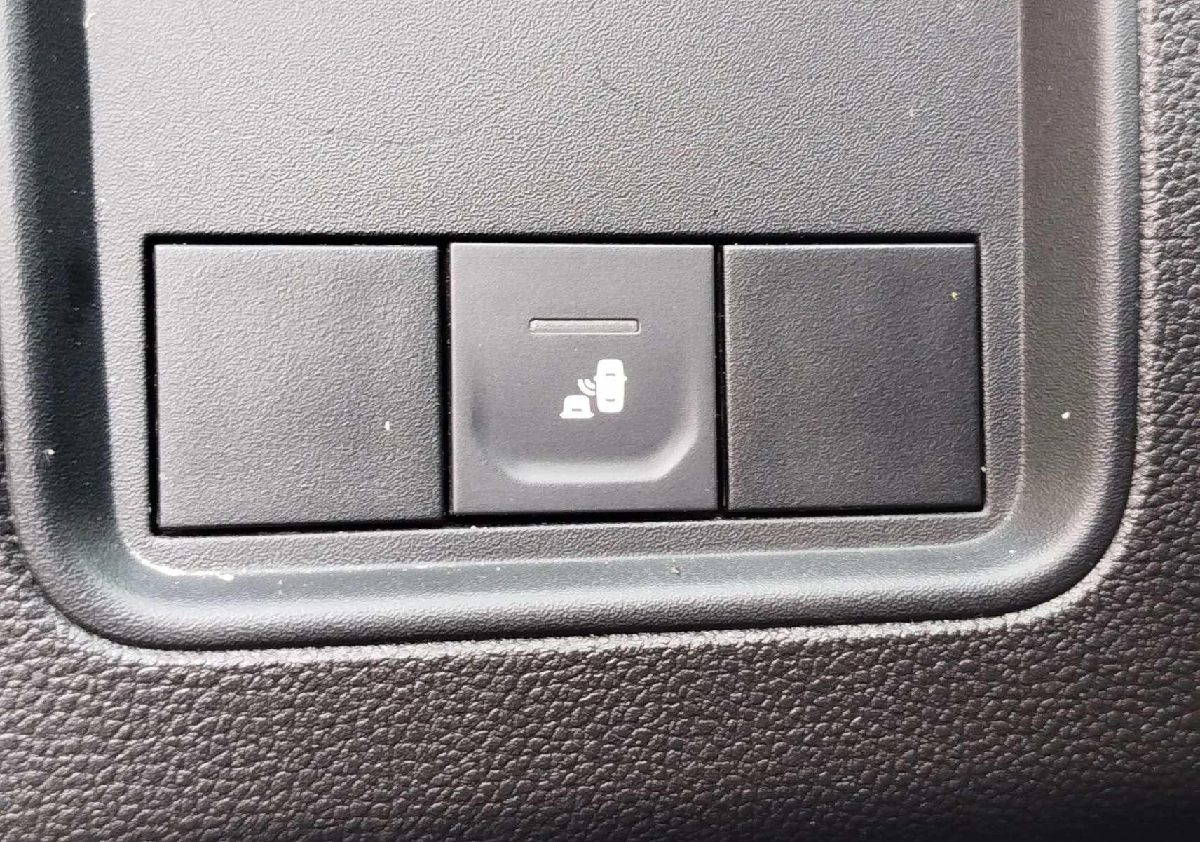 Gros plan sur le bouton de détection d'angle mort dans l'habitacle du Dacia Duster 2024 Vert Cèdre métallisé.