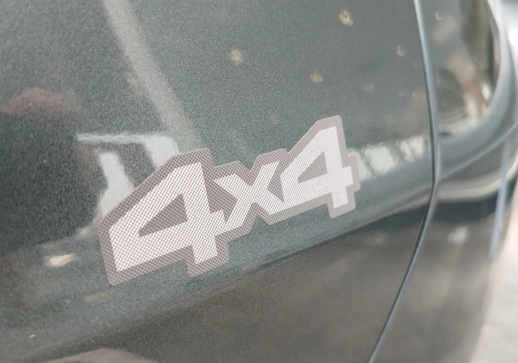 Gros plan sur l’autocollant 4x4 sur la portière d’un Dacia Duster Vert Cèdre métallisé 2024.