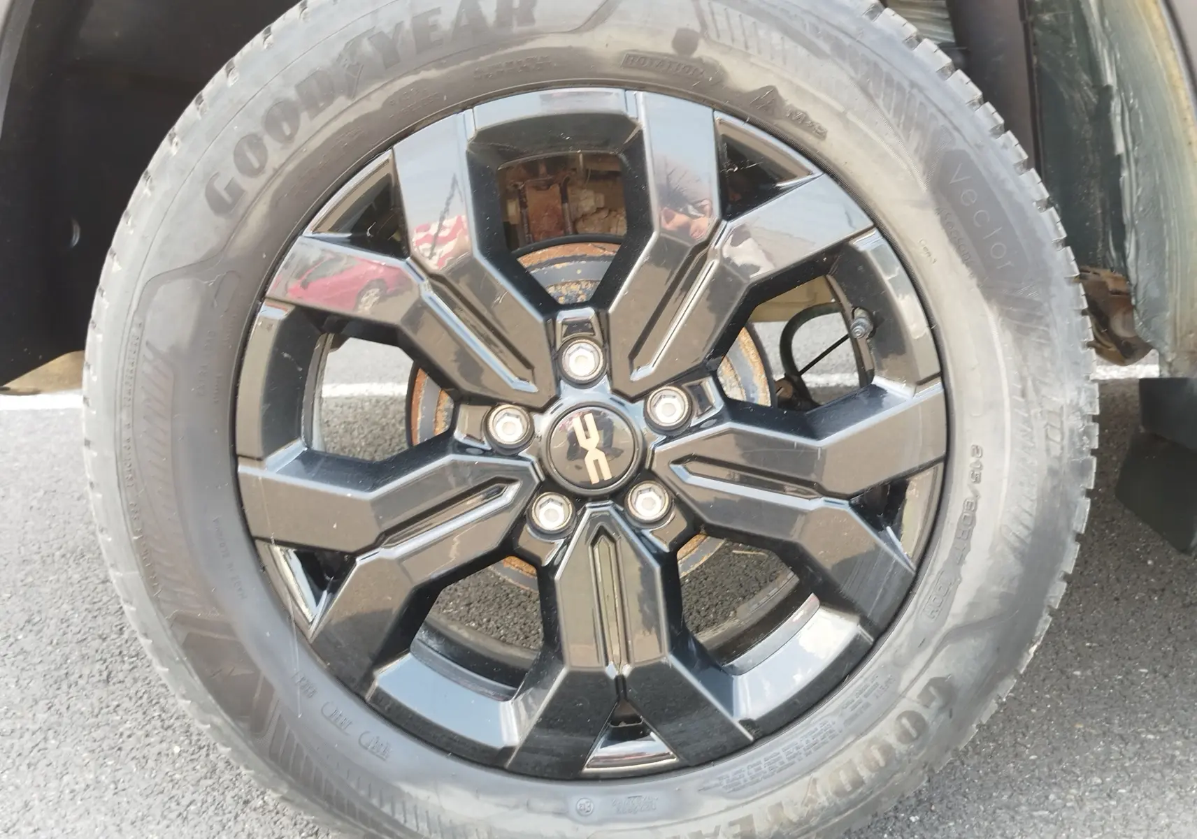 Gros plan sur la roue avant droite du Dacia Duster 2024 Vert Cèdre avec jante noire brillante et pneu Goodyear.