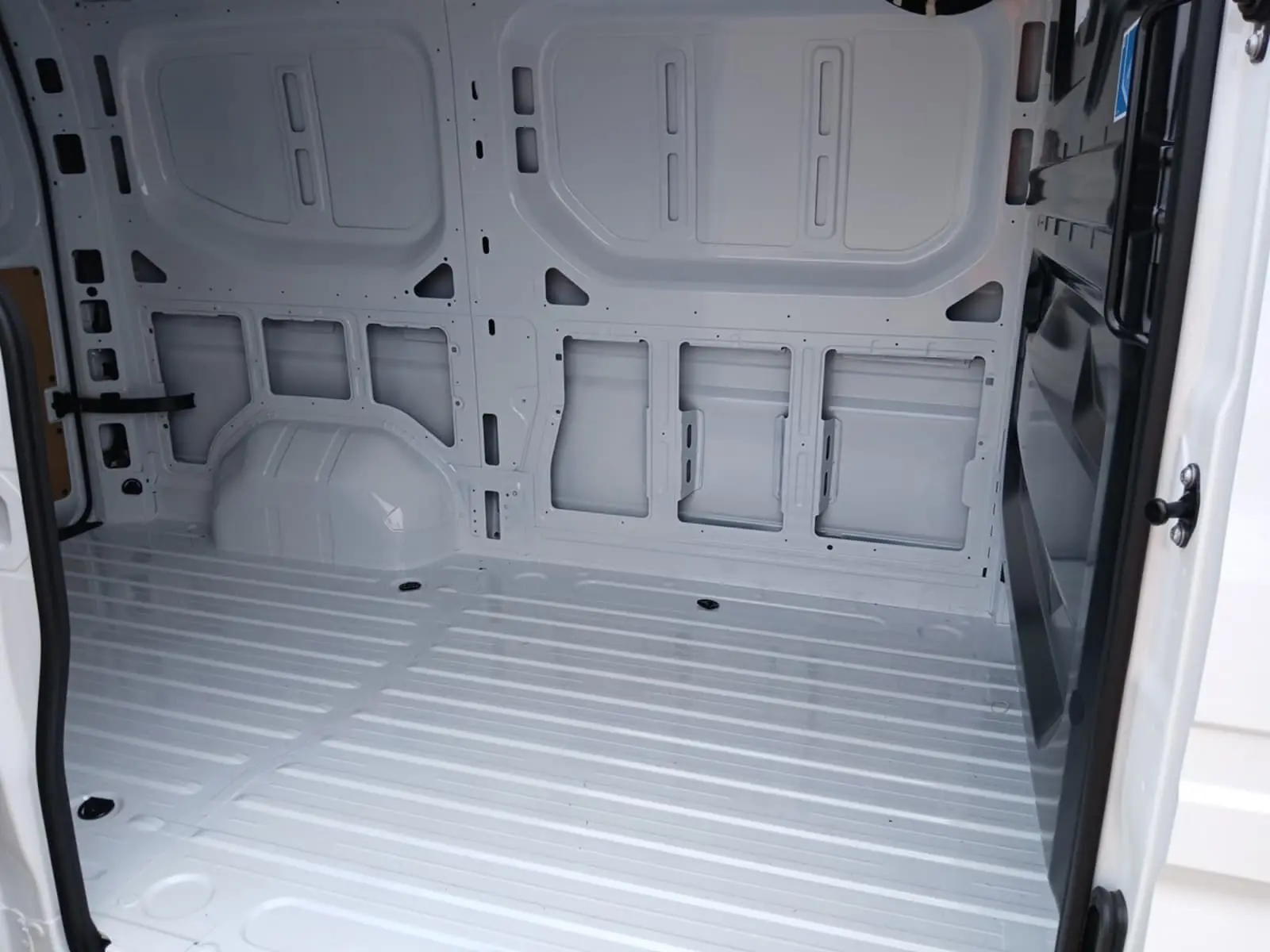 Intérieur vide du Renault Master blanc vu depuis l'ouverture latérale droite, montrant la structure métallique du fourgon.