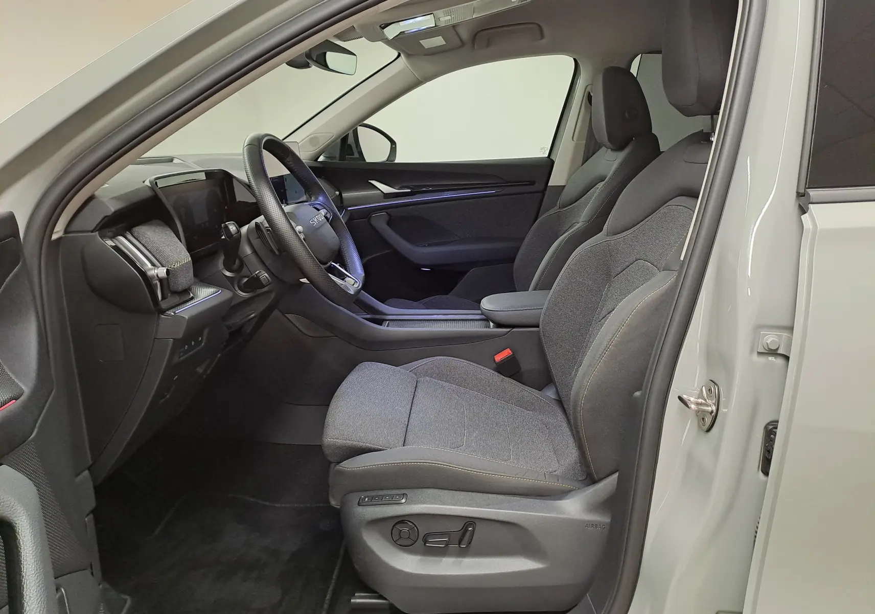 Vue intérieure côté conducteur du Skoda Kodiaq gris perle 2025, sièges tissu gris et tableau de bord moderne.