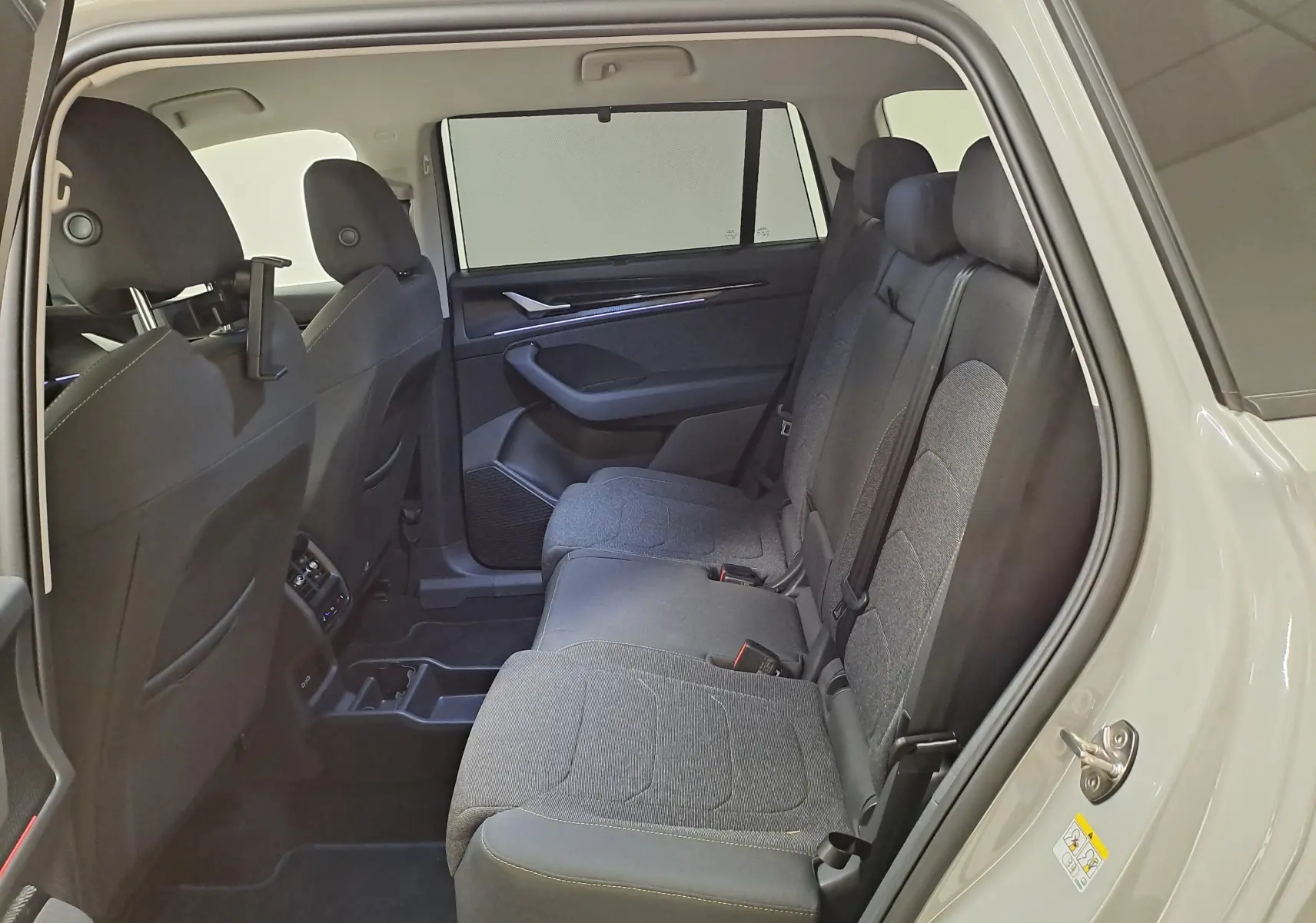 Vue intérieure côté droit des sièges arrière gris foncé du Skoda Kodiaq 2025, avec porte ouverte et habillage clair.