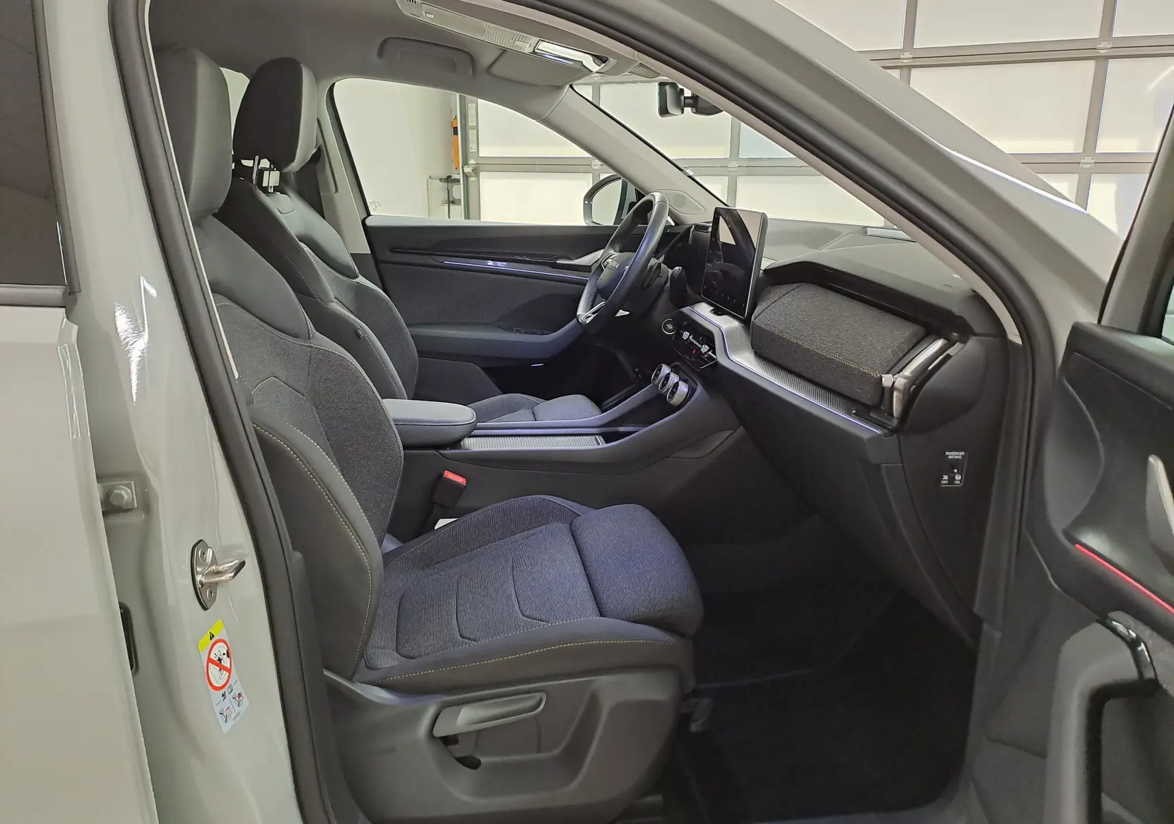Vue intérieure côté conducteur du Skoda Kodiaq gris perle 2025, avec sièges tissu et tableau de bord moderne.