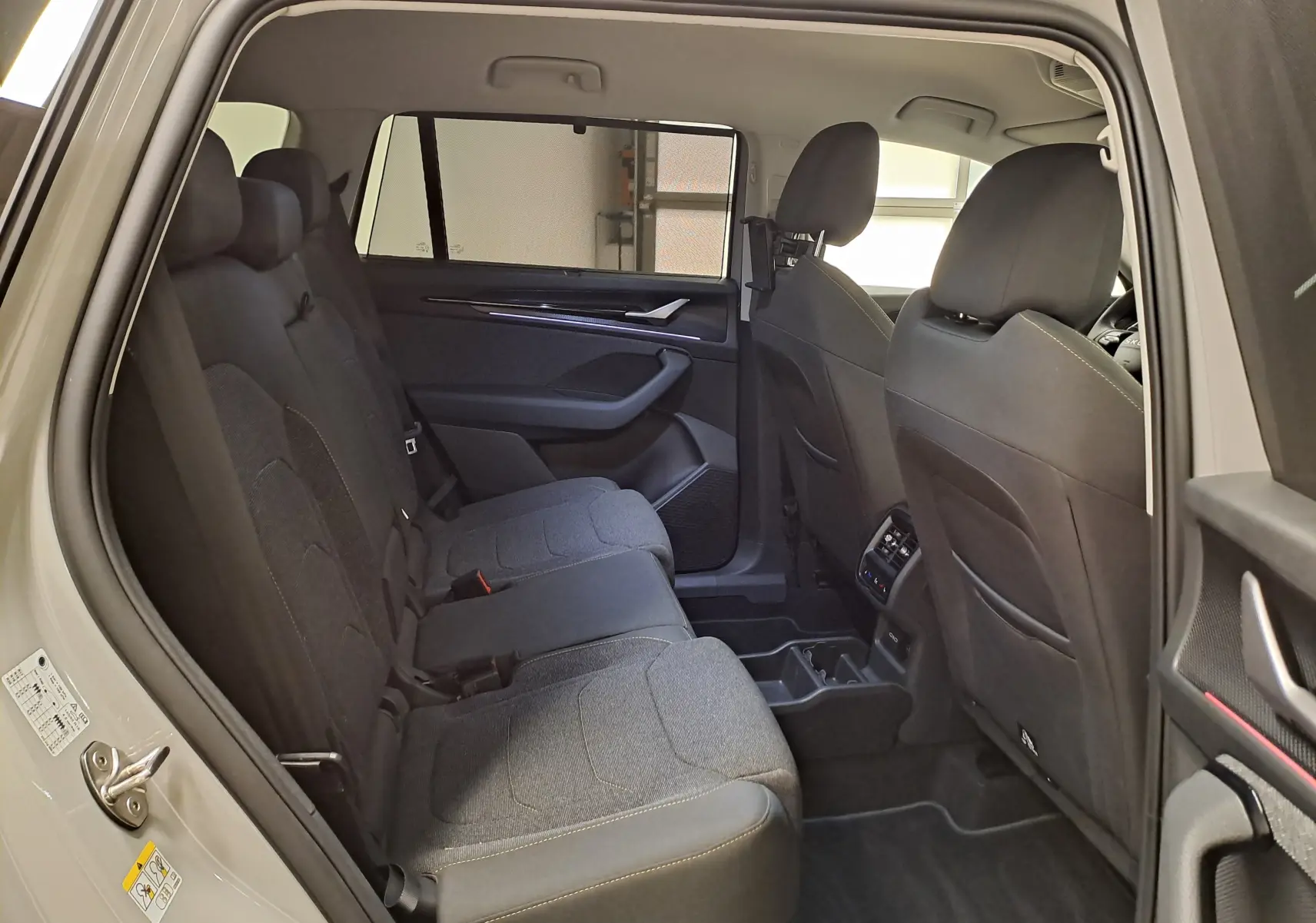 Vue intérieure côté gauche des sièges arrière du Skoda Kodiaq gris perle 2025, montrant l'habitacle spacieux et les finitions tissu.