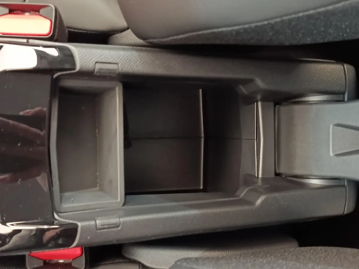Vue plongeante sur le rangement central noir de la Peugeot 208 électrique blanche, intérieur moderne et épuré.