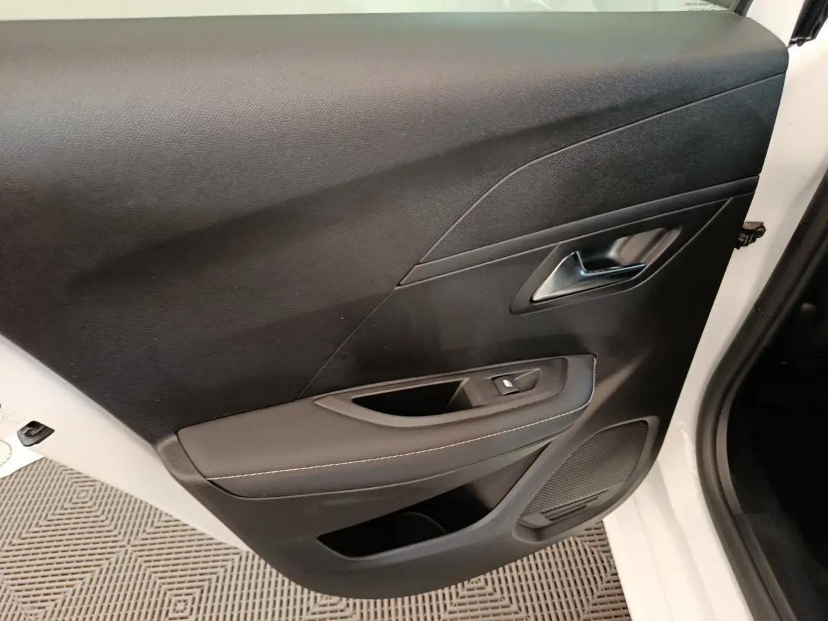 Vue rapprochée de la porte intérieure côté conducteur noire de la Peugeot 208 électrique blanche 2024.