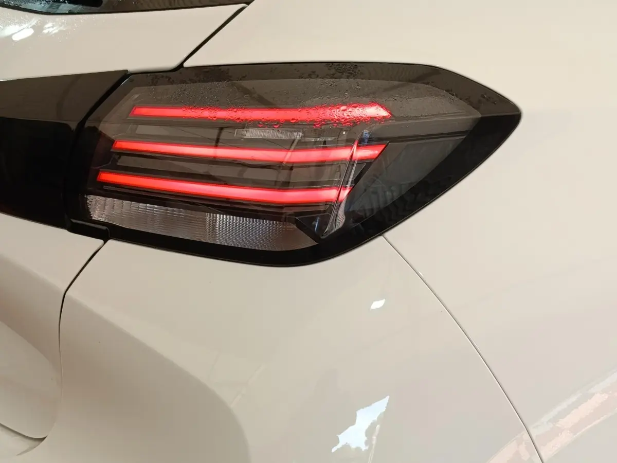 Gros plan sur le feu arrière droit rouge et noir d'une Peugeot 208 électrique blanche 2024.