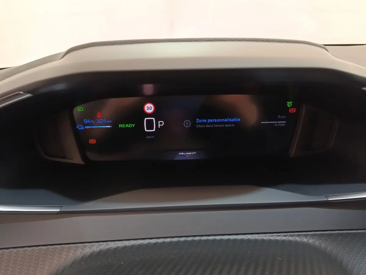 Affichage numérique du combiné instruments de la Peugeot 208 électrique 2024, avec indicateurs batterie et vitesse.
