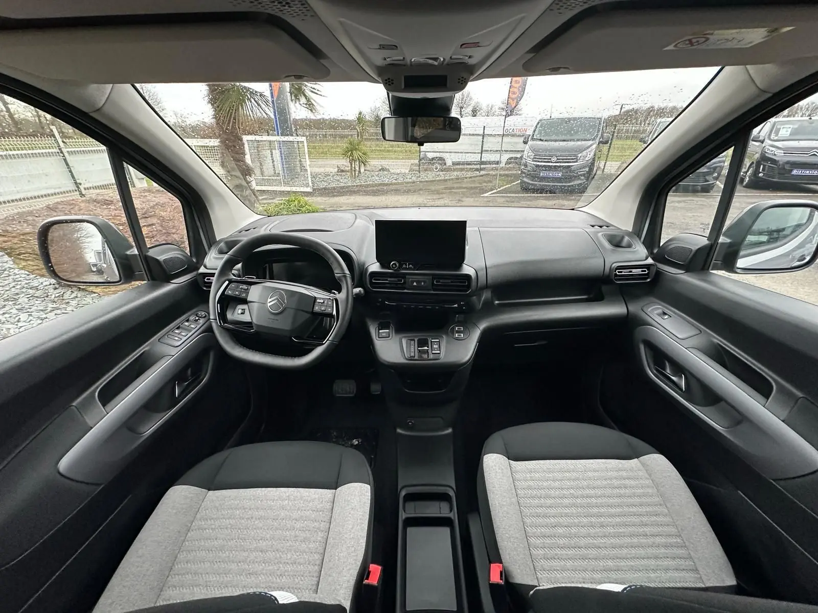 Vue intérieure avant du Citroën Berlingo 2025 gris Artense, montrant le tableau de bord et les sièges bicolores.
