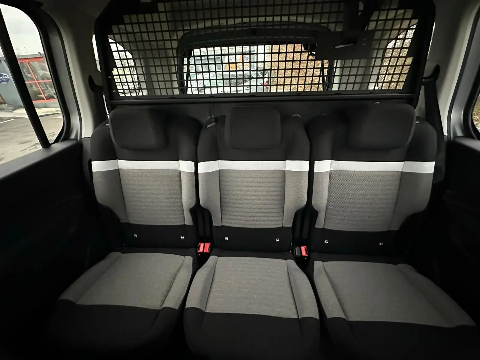 Vue intérieure arrière des sièges en tissu gris et noir du Citroën Berlingo N1 2025 avec séparation grillagée.