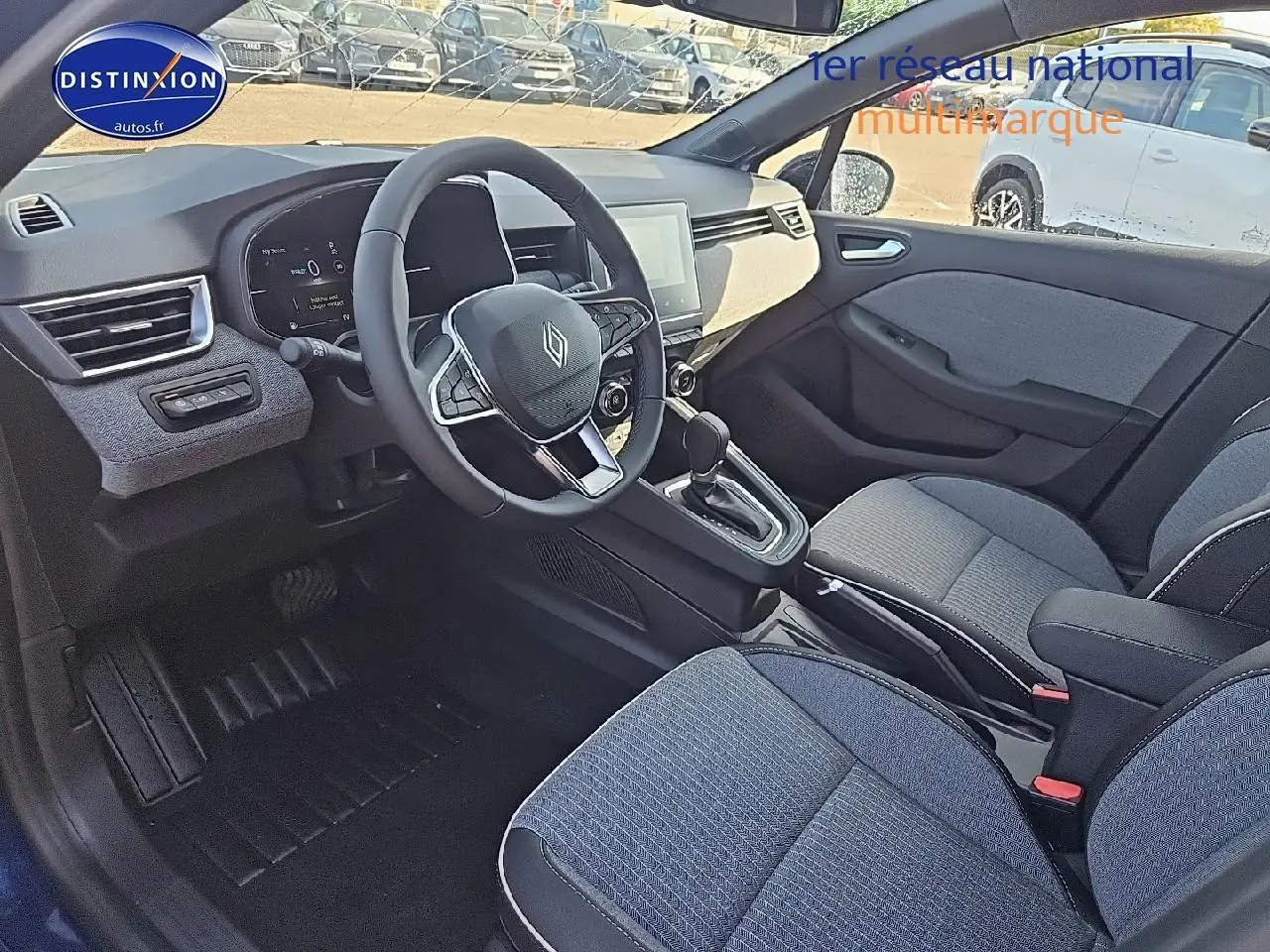 Intérieur avant droit de la Renault Clio V 1.6 e-tech 145 techno, sièges tissu bleu et console centrale avec boîte auto.