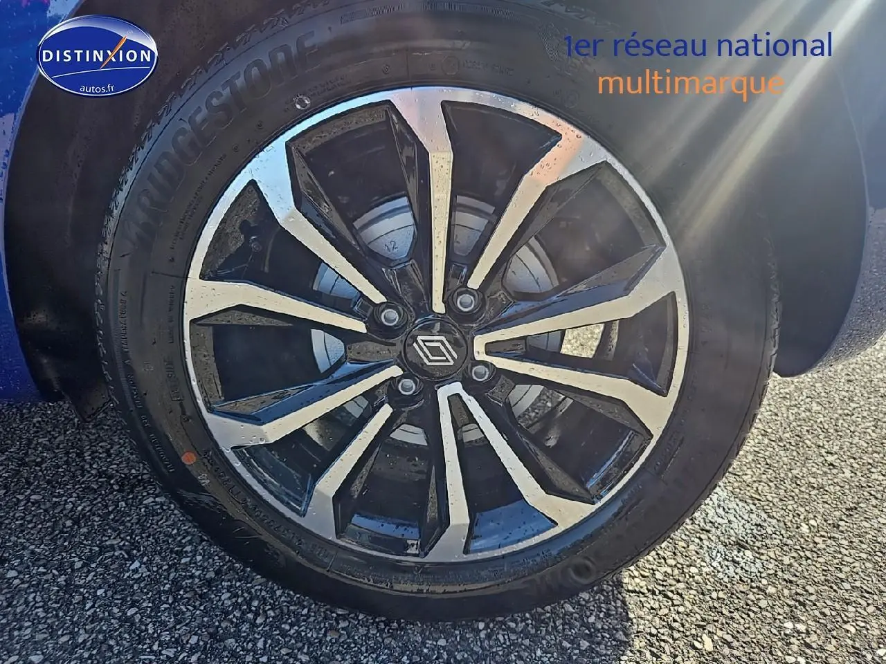 Gros plan sur la jante alu noire et argentée d'une Renault Clio V Bleu Iron, avec pneu Bridgestone visible.