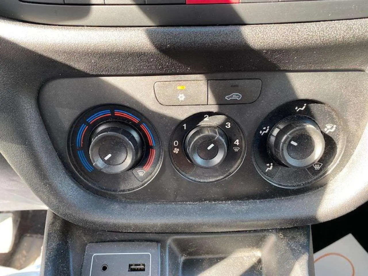 Détail du bouton de réglage de la climatisation avec indicateurs bleu et rouge dans un Fiat Doblo blanc de 2017.