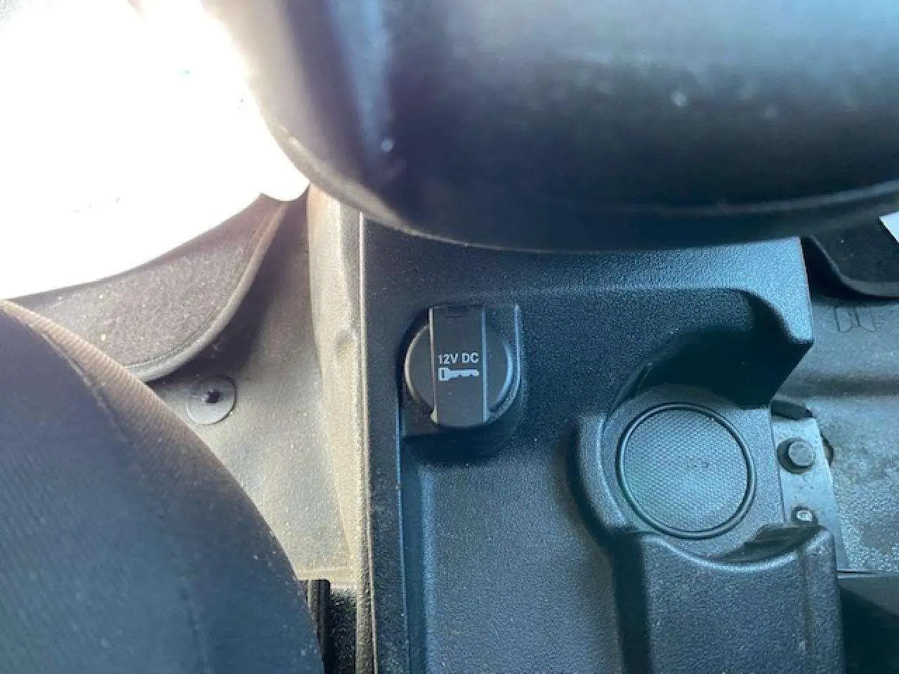 Prise 12V et porte-gobelet noir dans la console centrale du Fiat Doblo blanc, version fourgon 2017.