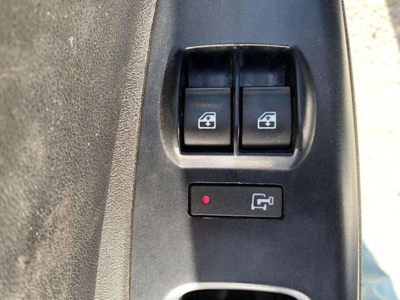 Gros plan sur les boutons de commande des vitres électriques du côté conducteur du Fiat Doblo blanc de 2017.