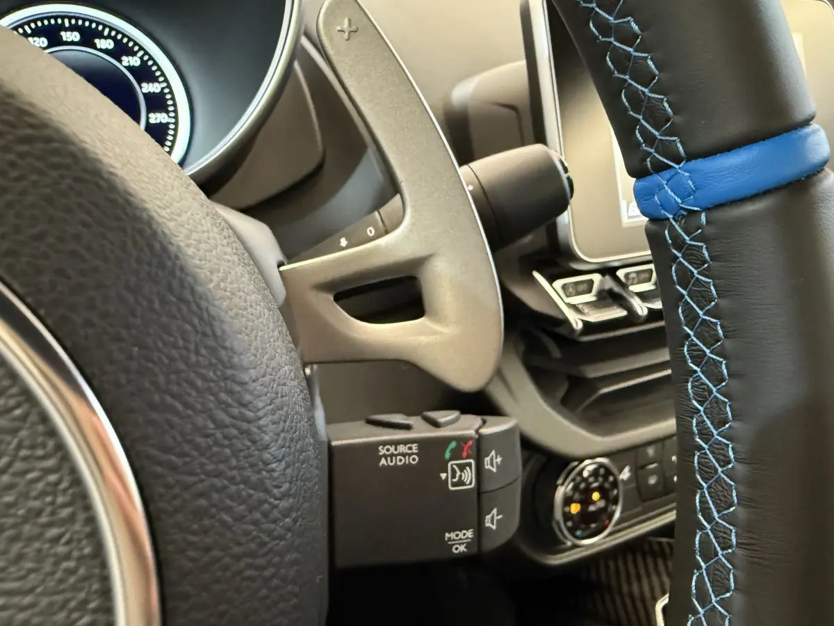 Gros plan sur le volant cuir noir avec surpiqûres bleues de l'Alpine A110 Legende 2019, tableau de bord partiel visible.