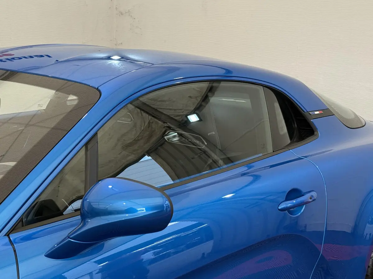 Vue latérale droite d'une Alpine A110 Legende 2019 bleu brillant avec rétroviseur et poignée de porte visibles.