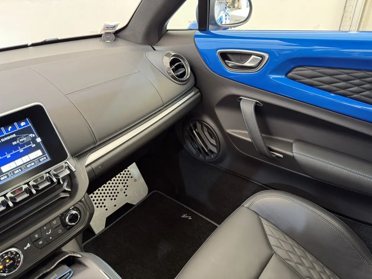 Vue intérieure côté passager de l'Alpine A110 Legende 2019 avec tableau de bord noir et insert bleu brillant sur la porte.
