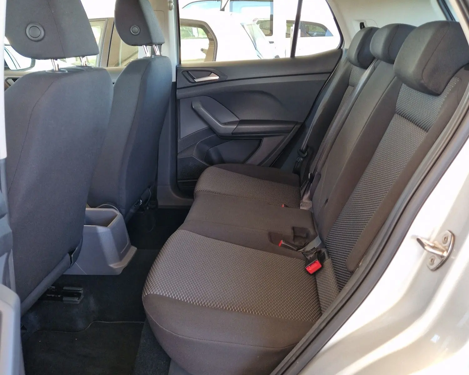 Intérieur arrière du Volkswagen T-Cross argent métal 2019, vue côté gauche avec sièges tissu gris et ceinture de sécurité rouge.