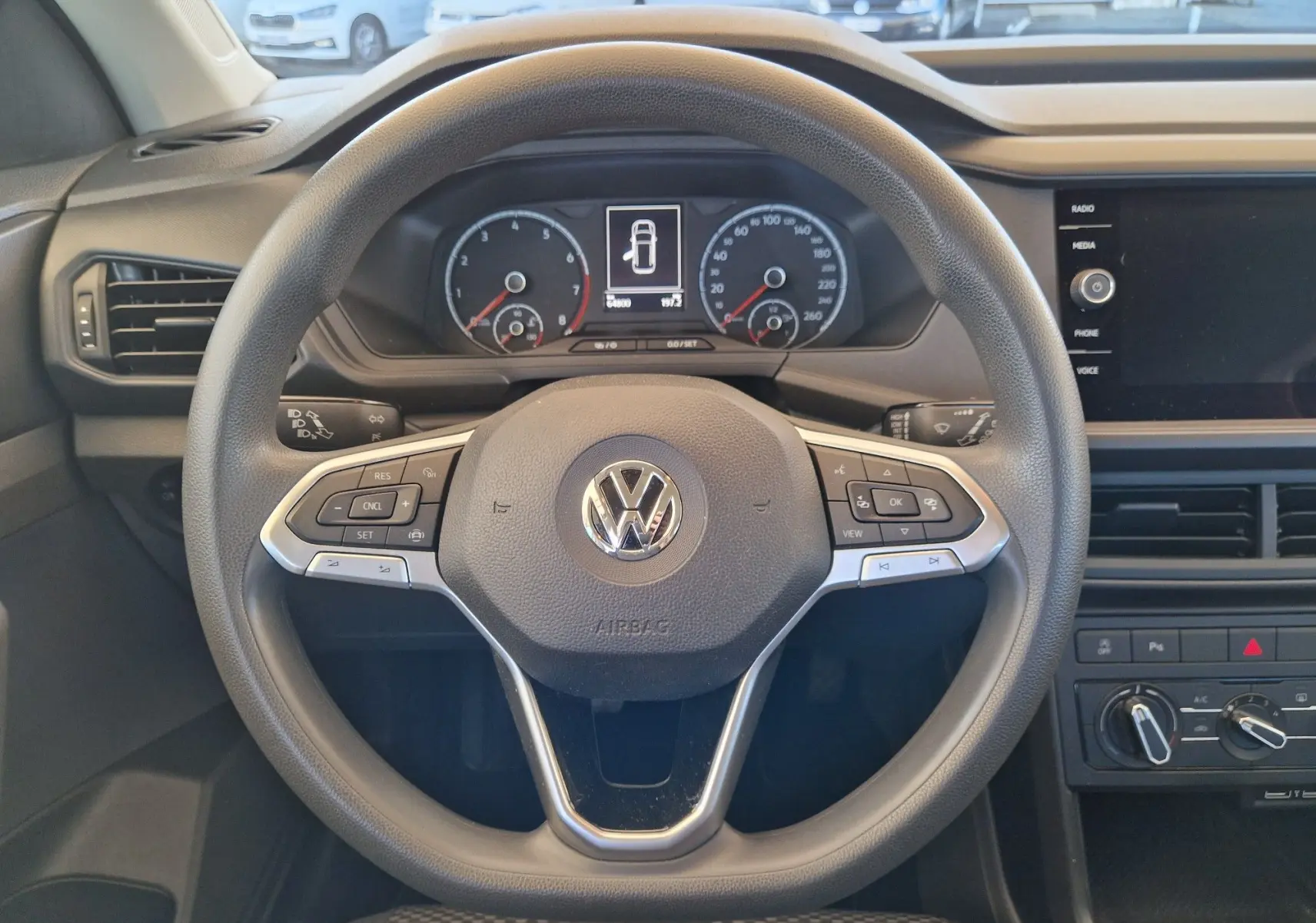 Vue rapprochée du volant multifonction d'un Volkswagen T-Cross 2019, avec tableau de bord numérique et commandes intégrées.