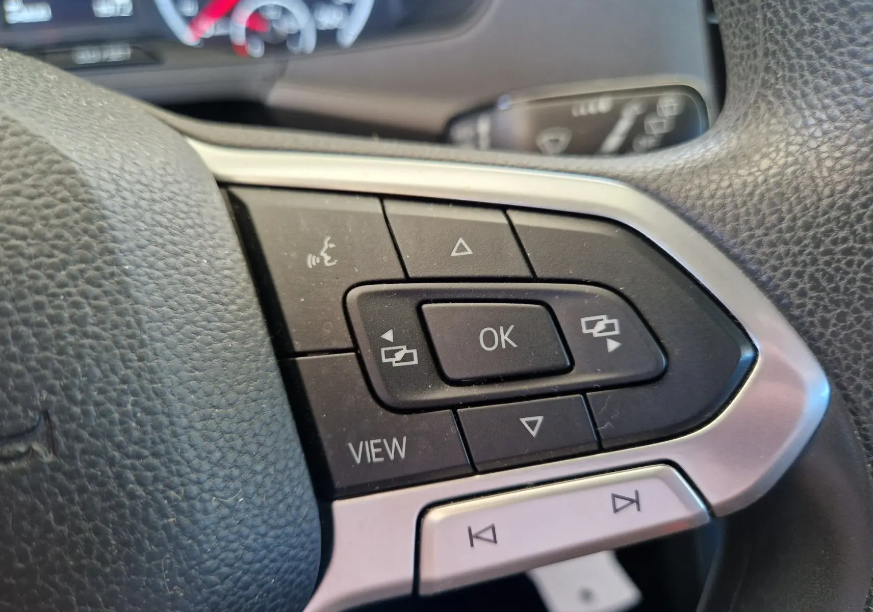Gros plan sur les commandes multifonctions à droite du volant en cuir noir du Volkswagen T-Cross argent métal 2019.