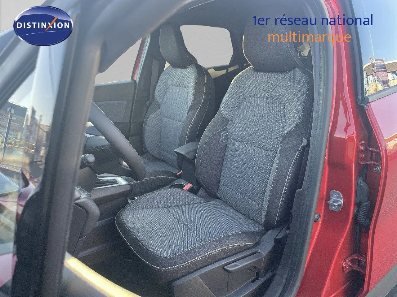 Vue intérieure côté conducteur du Renault Captur rouge passion, mettant en valeur les sièges en tissu gris foncé.