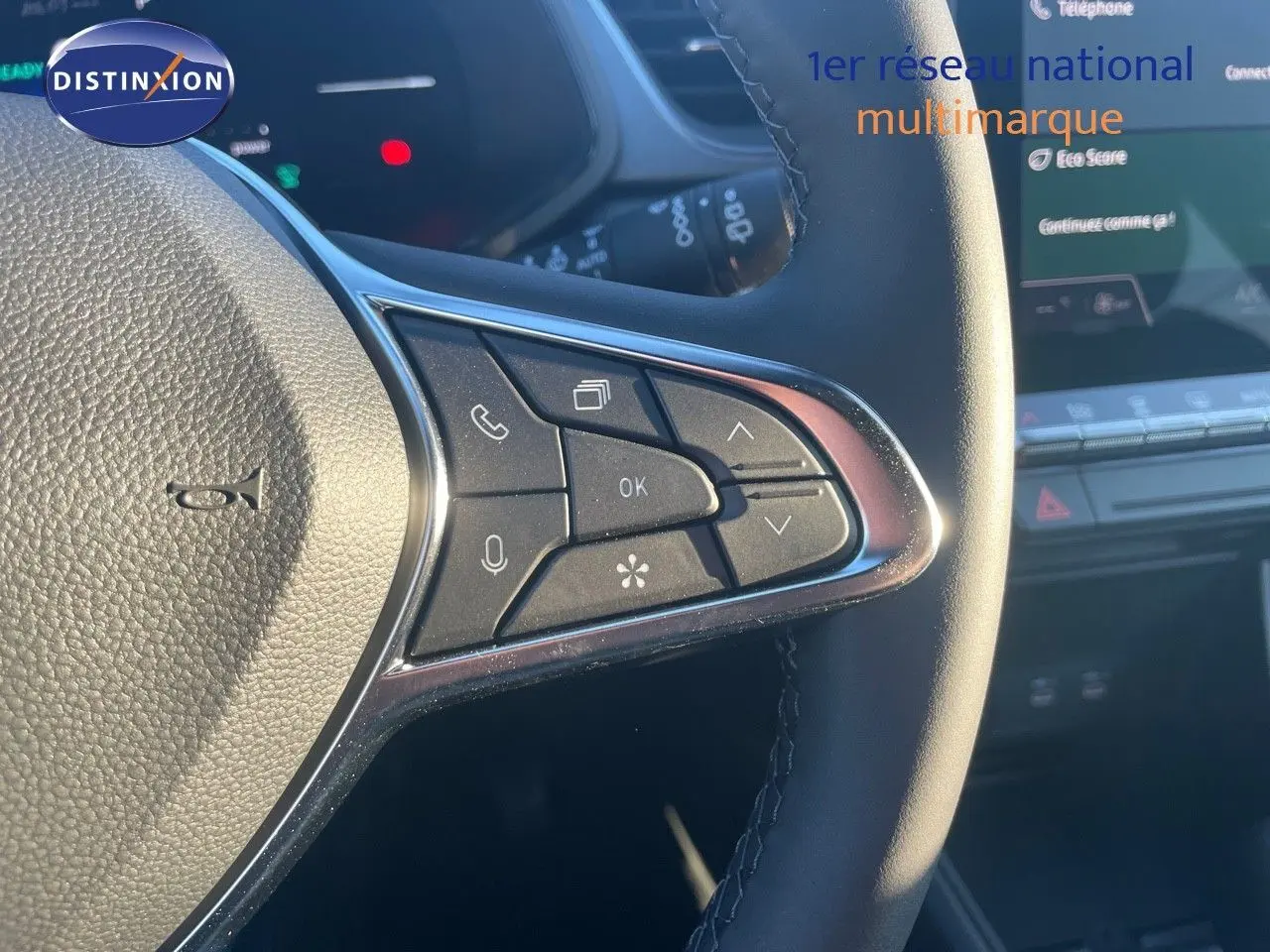 Gros plan sur les commandes au volant du Renault Captur E-Tech hybride rouge, avec tableau de bord numérique en arrière-plan.