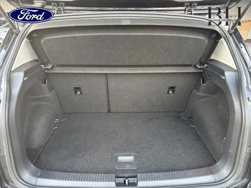 Coffre ouvert vu de l'arrière d'un Volkswagen T-Cross noir intense nacré, espace de chargement vide et propre.