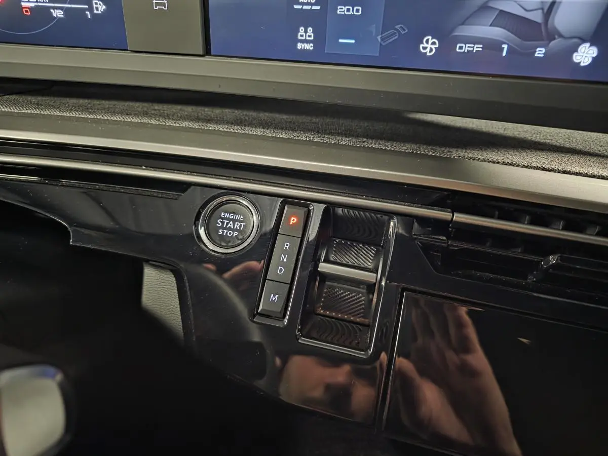 Détail de la console centrale noire brillante du Peugeot 5008 blanc, avec bouton start/stop et sélecteur de boîte automatique.