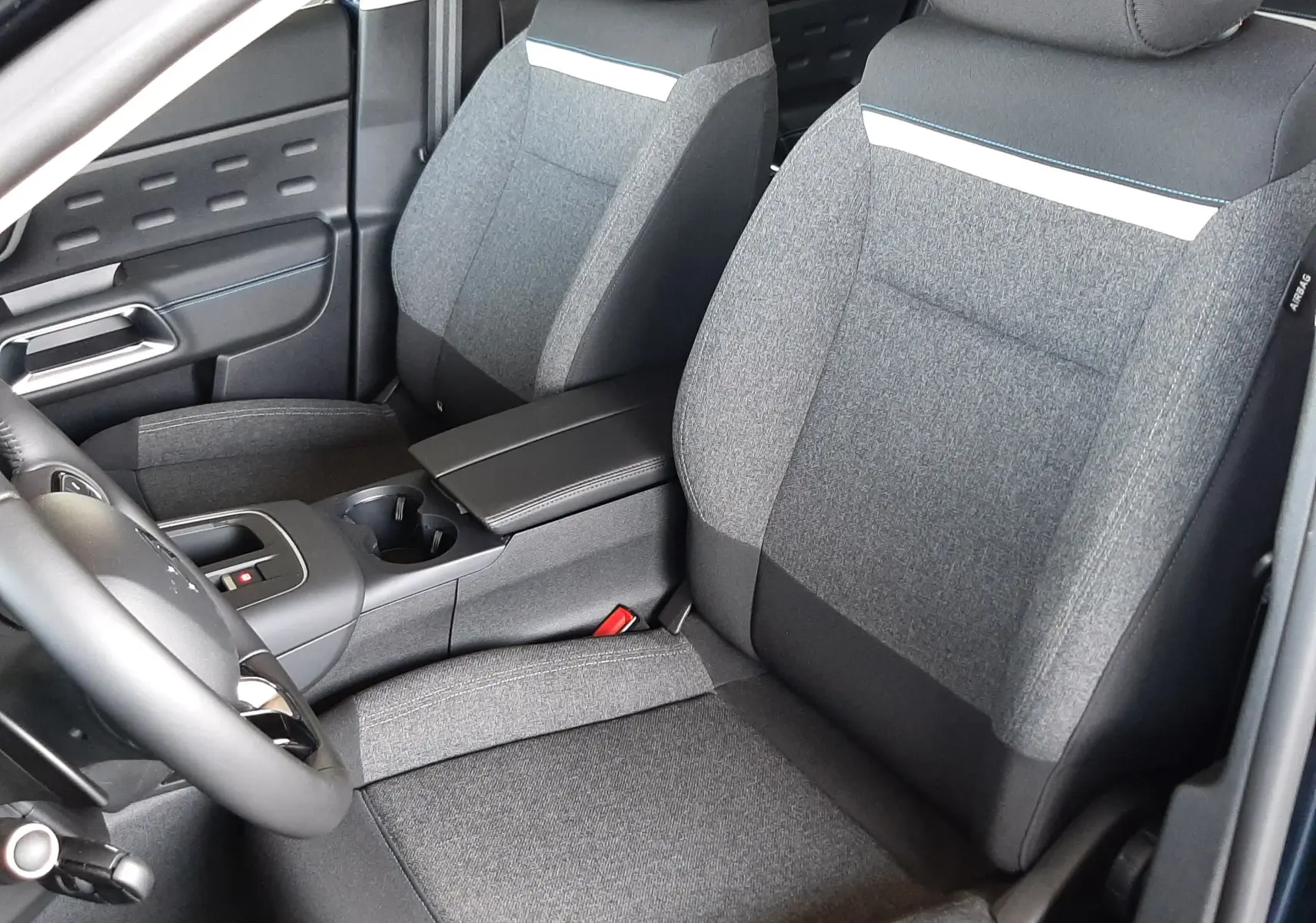Vue intérieure côté avant gauche du Citroën C5 Aircross 2025, sièges tissu gris avec bande blanche décorative.