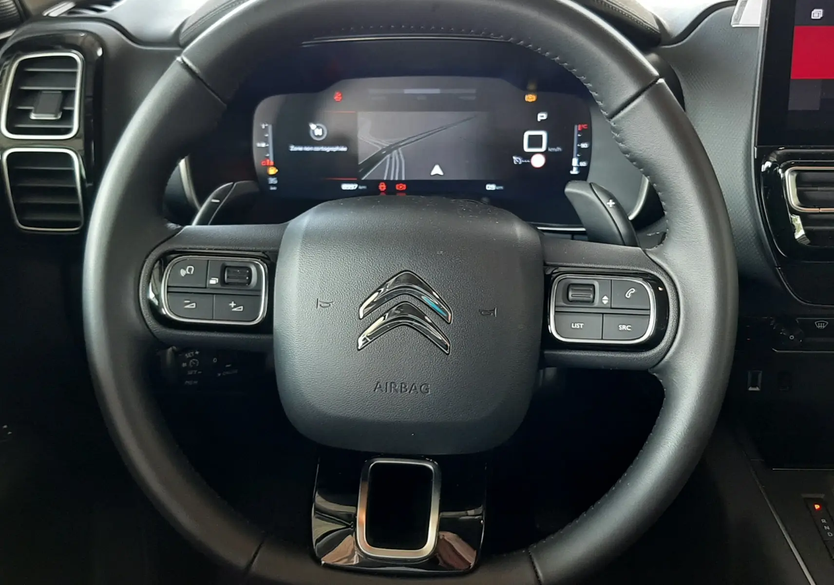 Vue rapprochée du volant noir du Citroën C5 Aircross 2025 avec tableau de bord numérique et commandes intégrées.