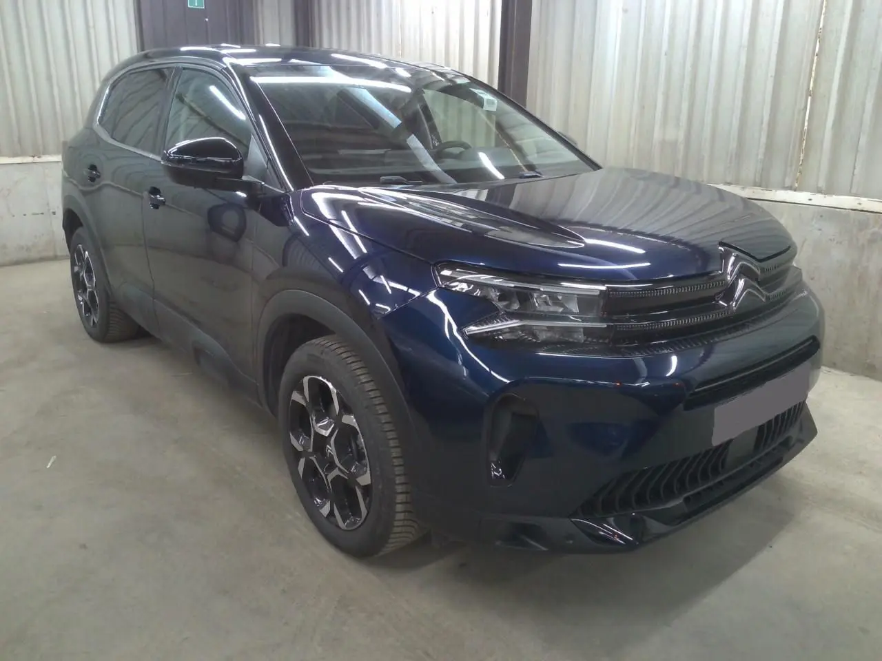 Vue 3/4 avant droite du Citroën C5 Aircross 2025 bleu éclipse avec calandre distinctive et jantes noires bicolores.