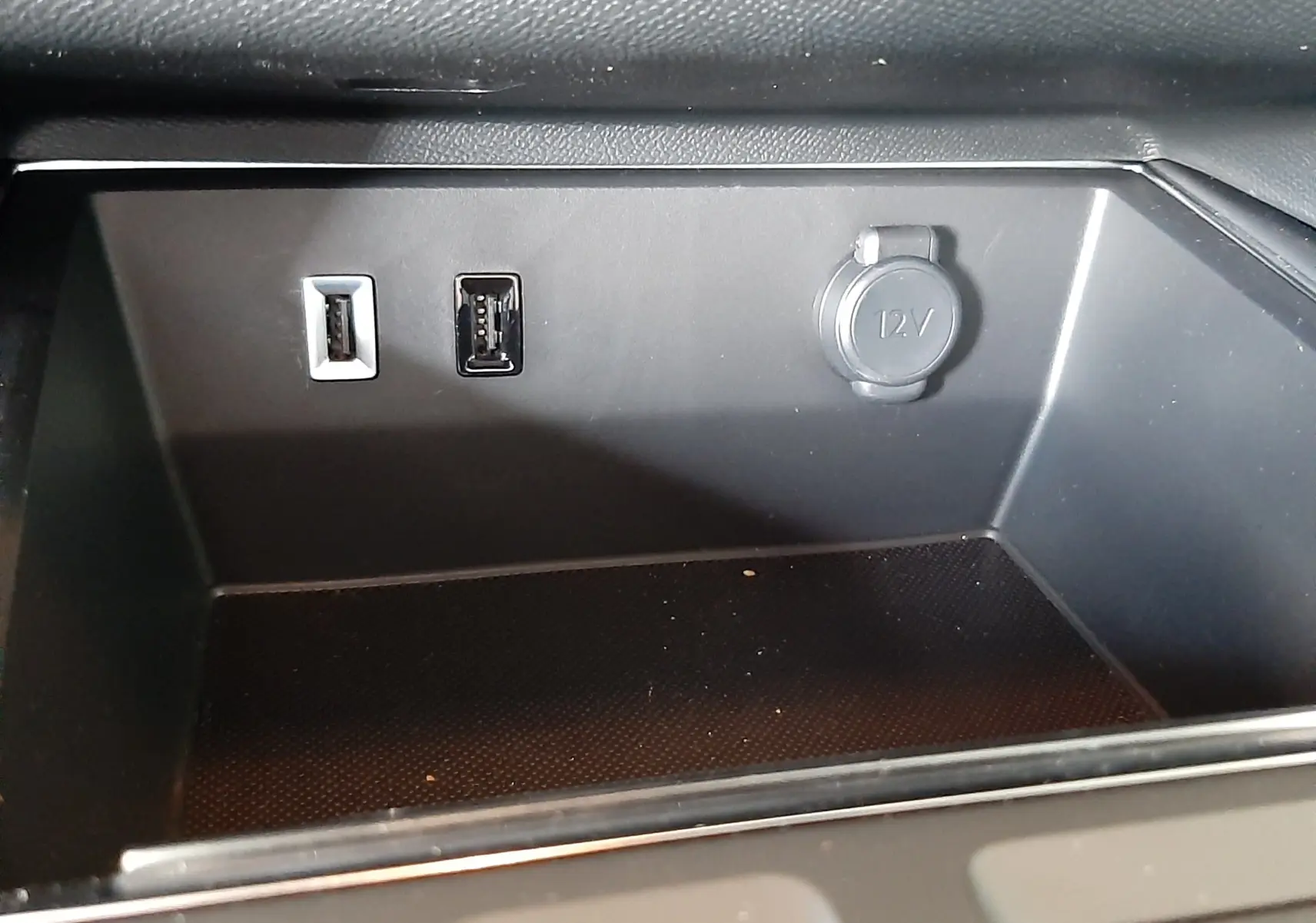 Gros plan sur la console centrale du Citroën C5 Aircross 2025, montrant les ports USB et la prise 12V dans un intérieur noir.