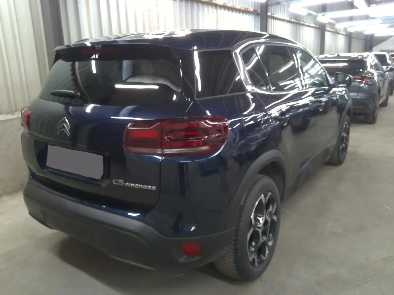 Vue 3/4 arrière droite du Citroën C5 Aircross bleu éclipse avec feux arrière allongés et jantes noires distinctives.
