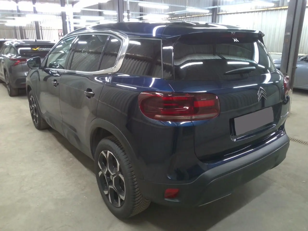 Vue 3/4 arrière droite du Citroën C5 Aircross 2025 bleu éclipse avec feux arrière distinctifs et jantes stylisées.