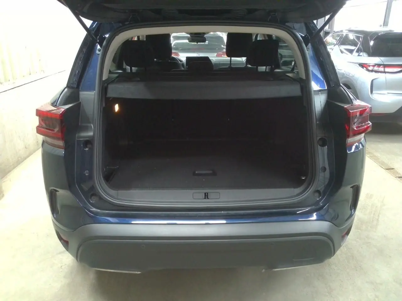 Vue arrière du Citroën C5 Aircross 2025 bleu éclipse avec coffre ouvert montrant l’espace de chargement vide.
