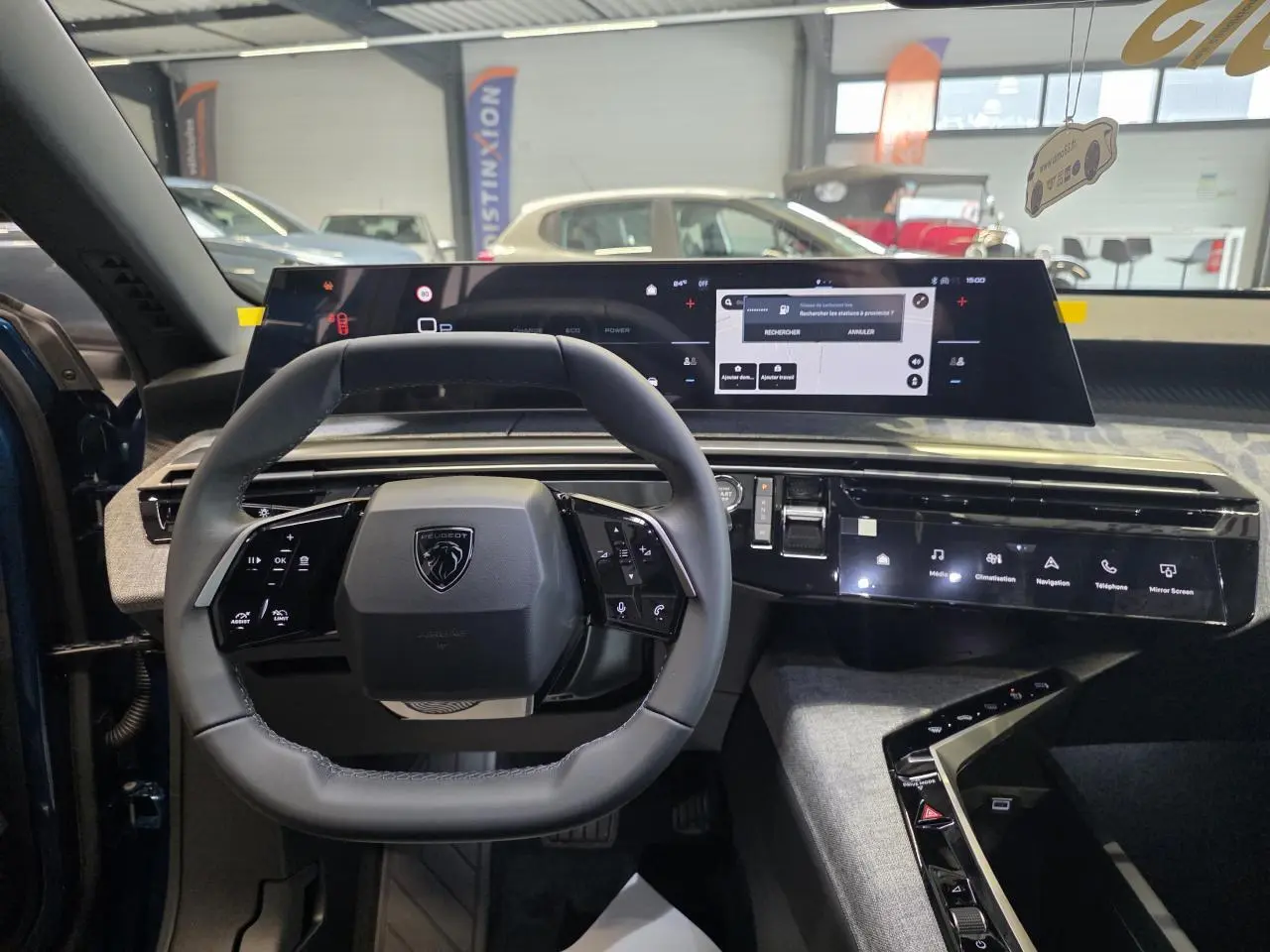 Vue intérieure centrée sur le volant compact et l'écran panoramique du tableau de bord du Peugeot 3008 hybride 2026.