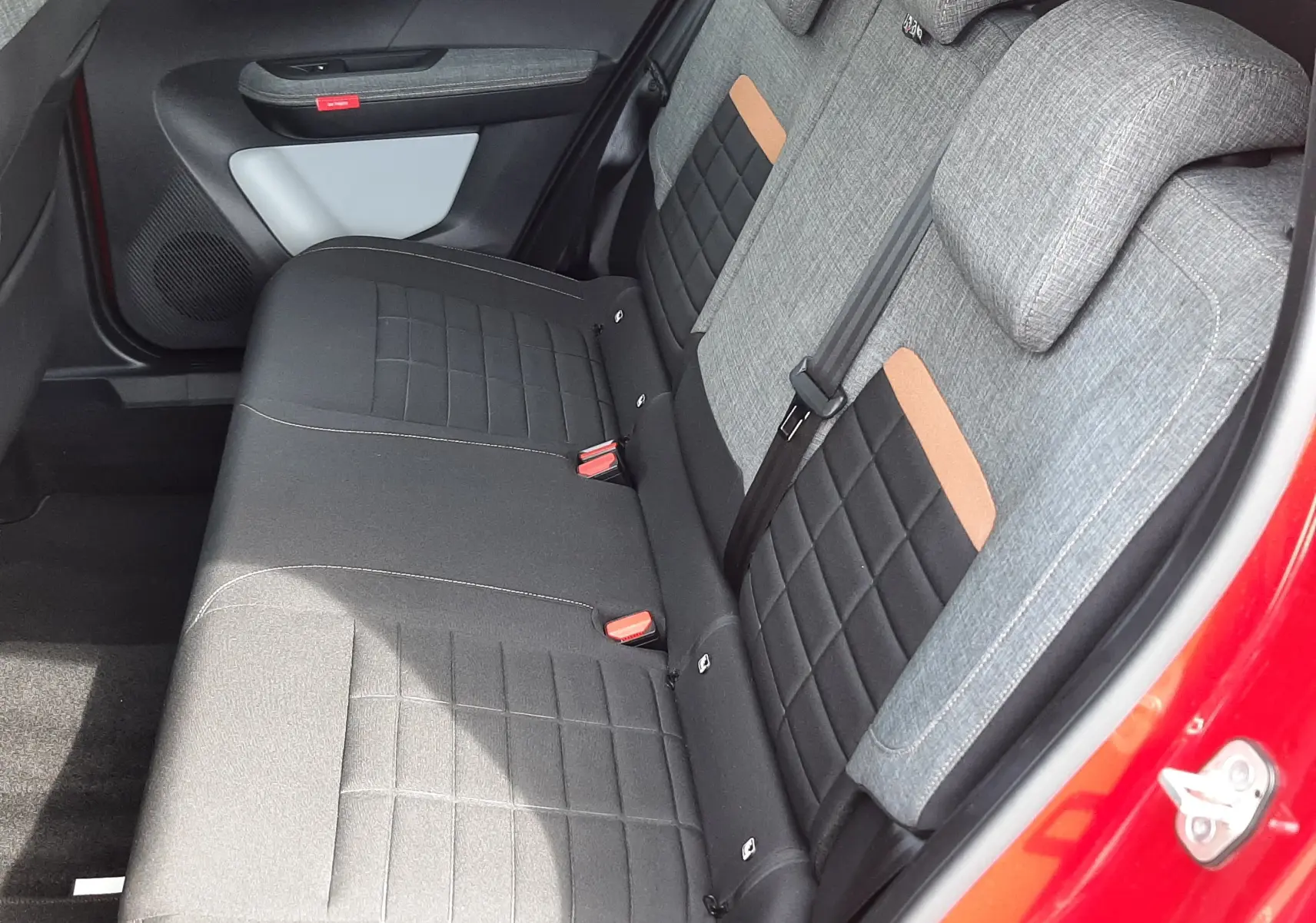 Vue intérieure côté arrière droit du Citroën C3 Aircross rouge Elixir, sièges arrière gris et noir avec inserts marron.