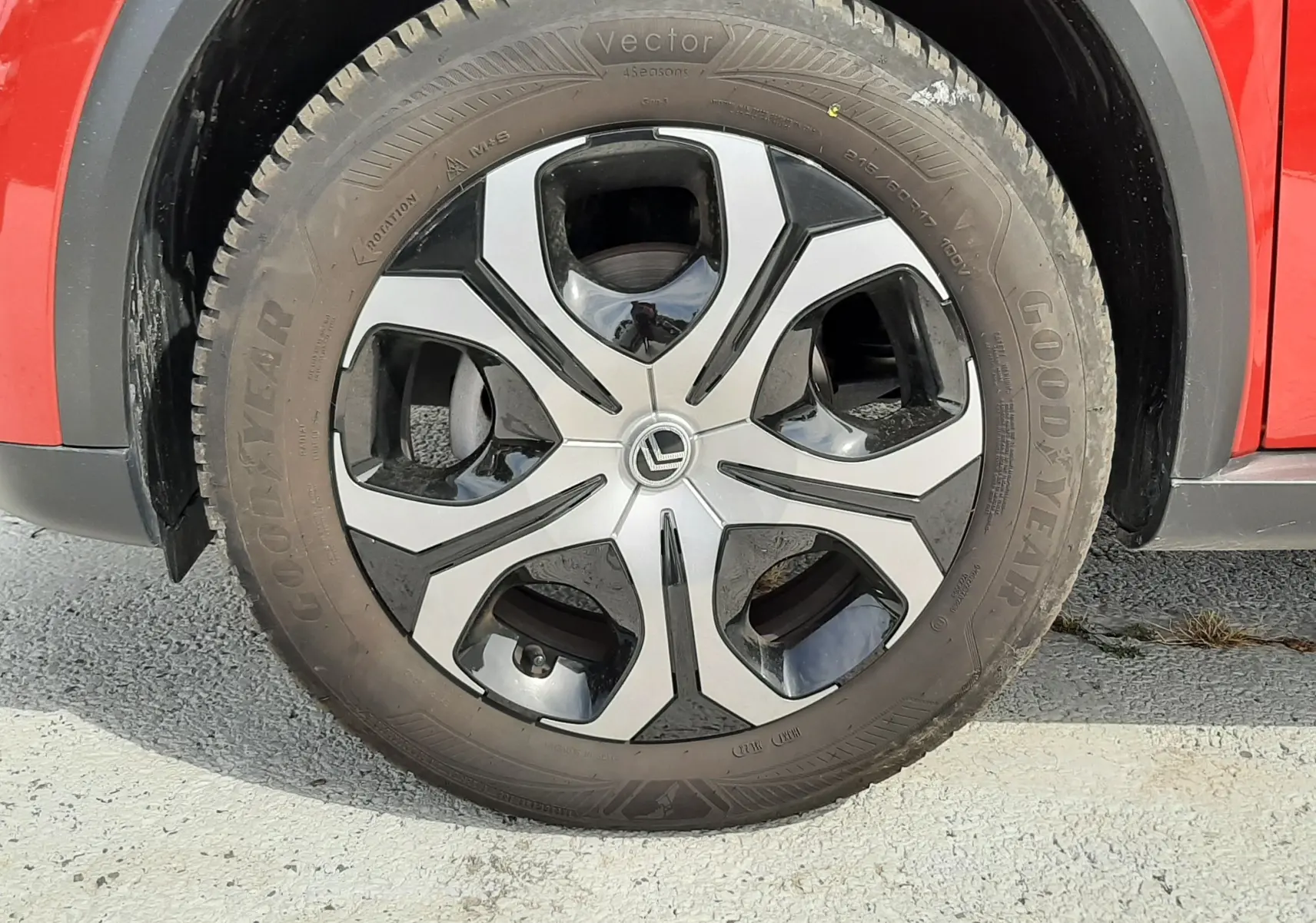 Gros plan sur la roue avant gauche d'une Citroën C3 Aircross rouge Elixir avec jante alliage bicolore et pneu Goodyear.