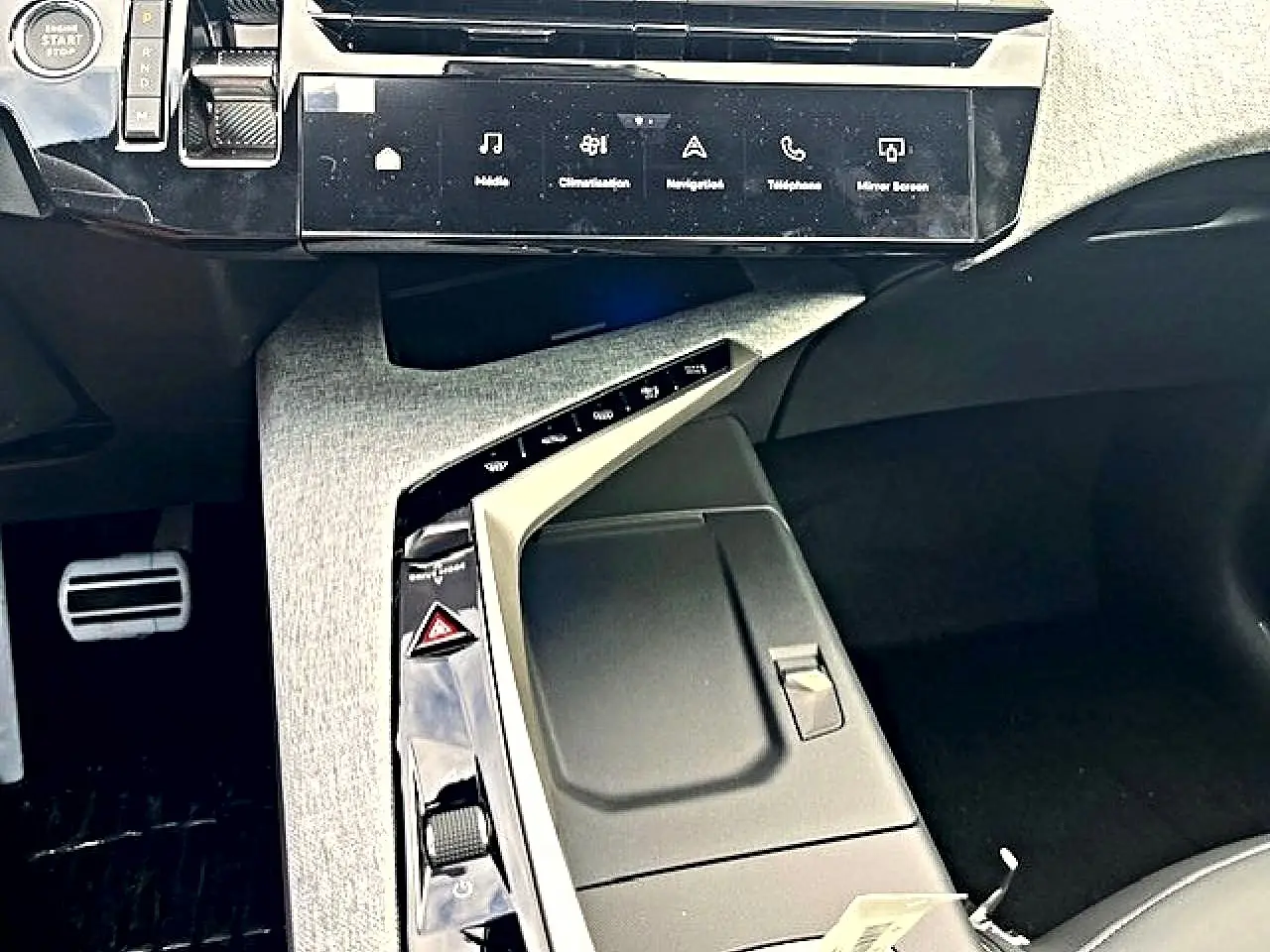 Vue intérieure centrée sur la console centrale grise et noire du Peugeot 3008 hybride avec écran tactile et commandes modernes.